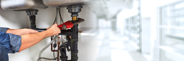 Professional plumber working in kitchen plumbing repairs.