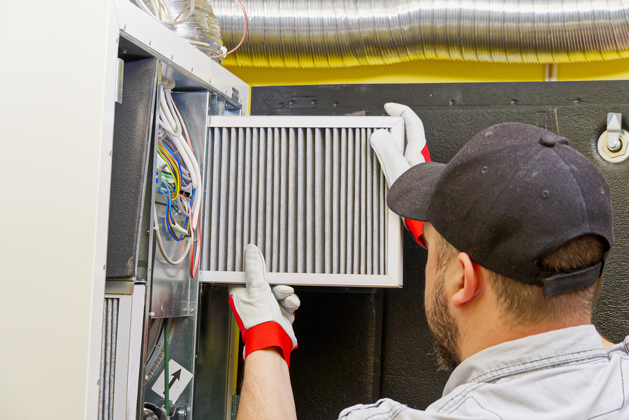 Furnace service technician changing dirty air filter in the furnace
